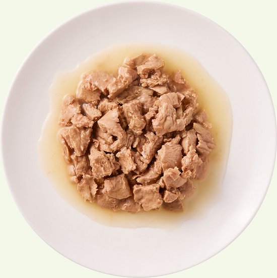 YARRAH BIOLOGISCHE KATTENVOER FILETS MET KALKOEN IN SAUS 14X85 GR in een witte kom met saus.