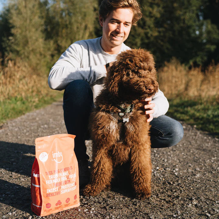 Man met hond in de natuur met Imby Hypoallergene mini hondenvoer zak.